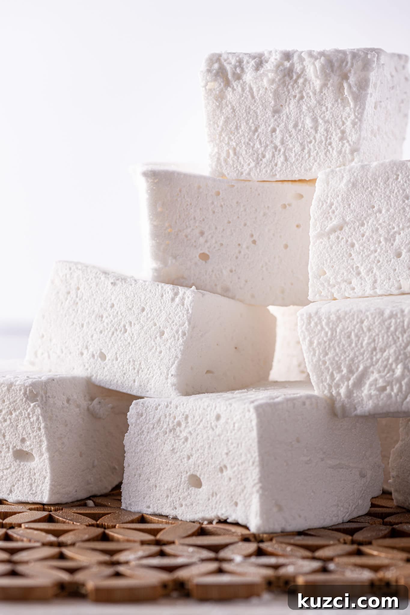 Stack of fluffy square shaped sugar free marshmallows on a bright white background.