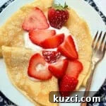 three plated crepes topped with fresh strawberries and whipped cream