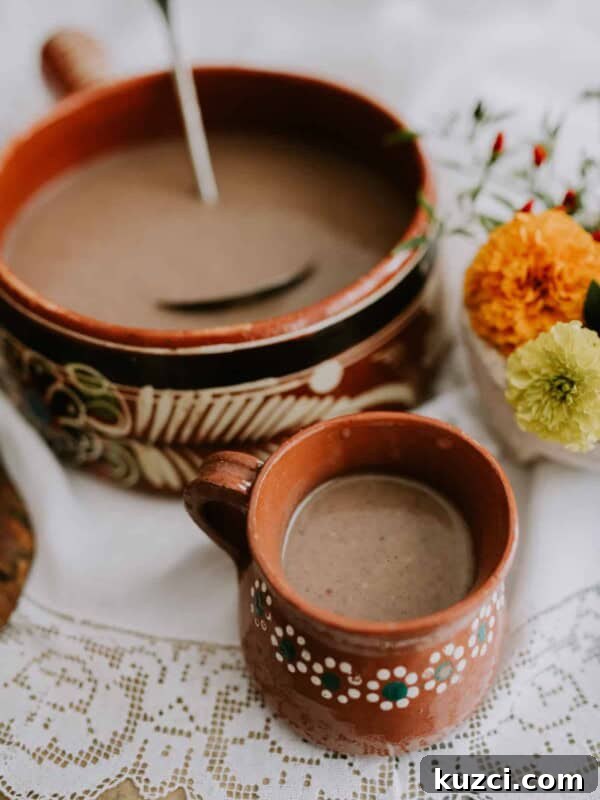 Witches' Brew Sangria: Spooky Halloween Cocktail 11 Mexican Hot Chocolate in Mexican barro pot next to a matching mug filled with Mexican hot chocolate.