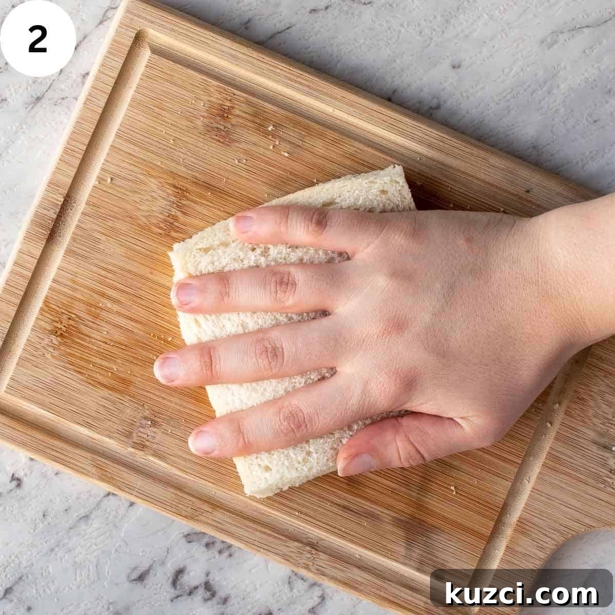 Pressing on  a white bread sandwhich with hand.
