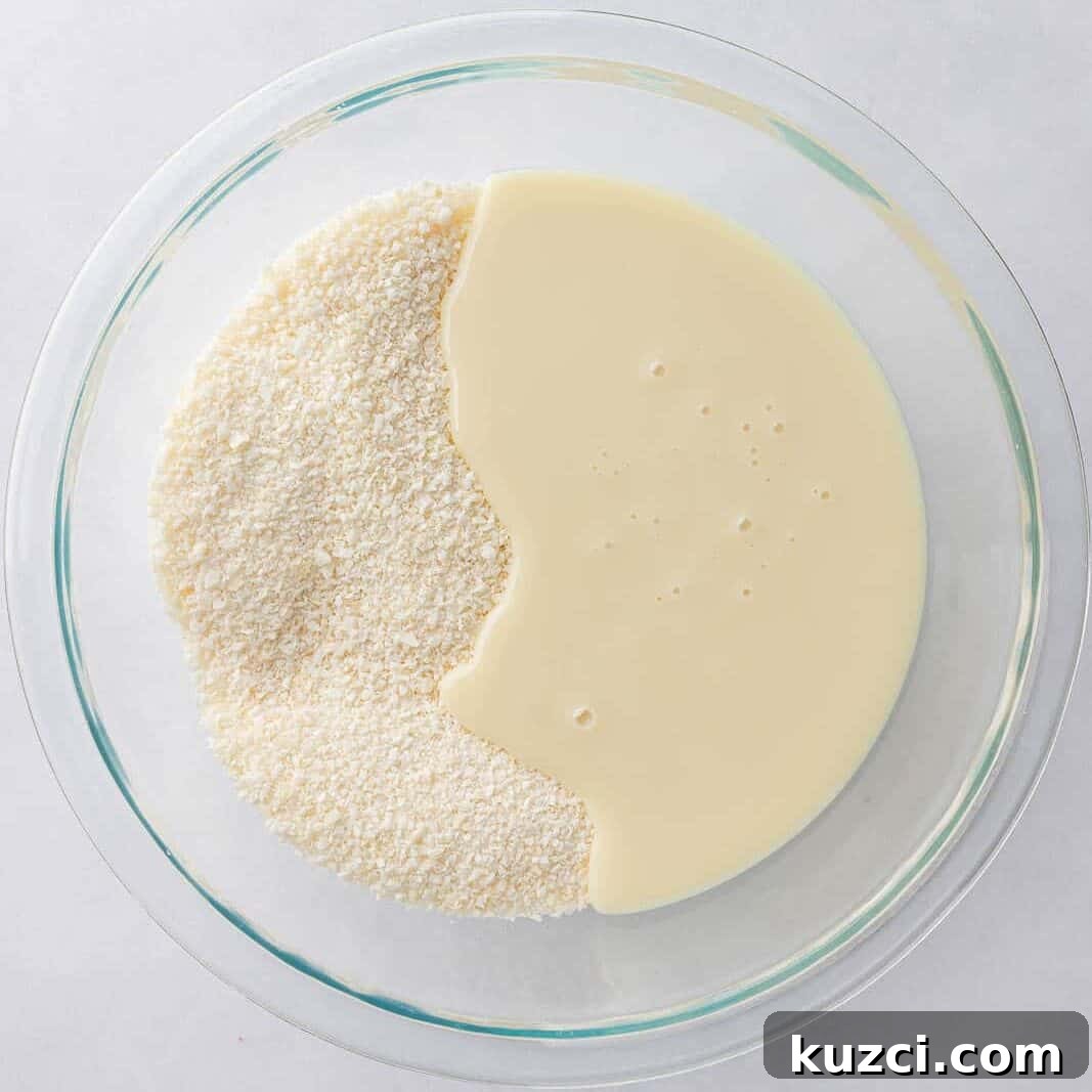 No-Bake Coconut Chocolate Bar Recipe 4 Coconut and condensed milk are mixed together in a bowl.