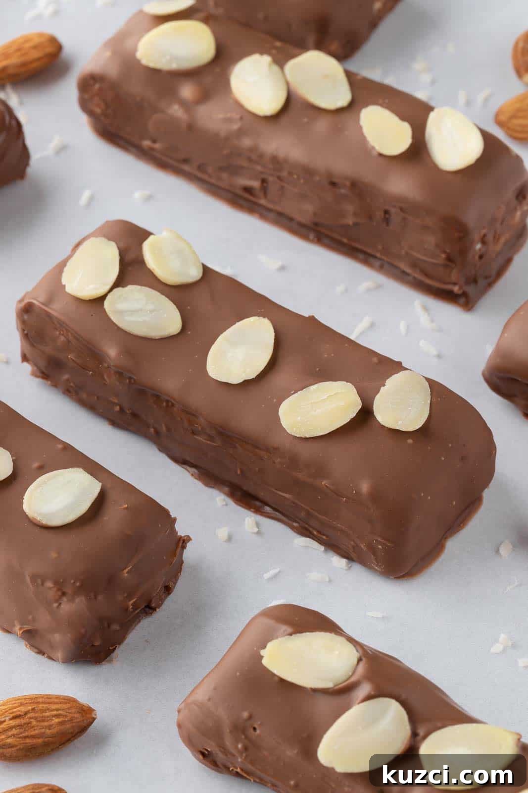 No-Bake Coconut Chocolate Bar Recipe 10 Candy bars topped with slivered almonds on a tray.