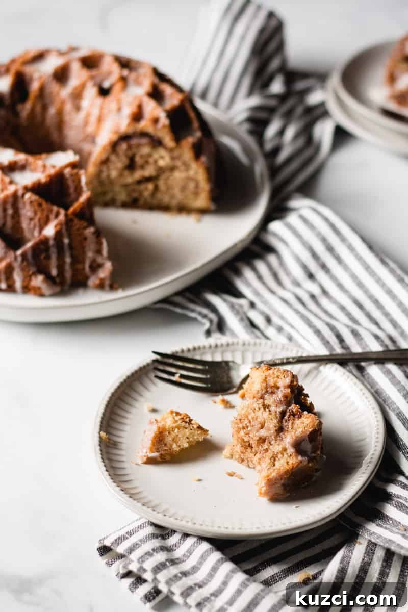 a half eaten slice of sour cream coffee cake on a white plate.