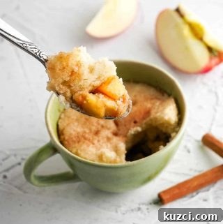 Spoon with apples and cake being held over top cake in a green mug
