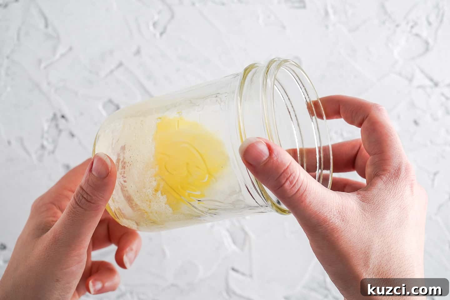 Microwave Apple Cinnamon Mug Cake Recipe 8 Two hands holding glass with melted butter inside