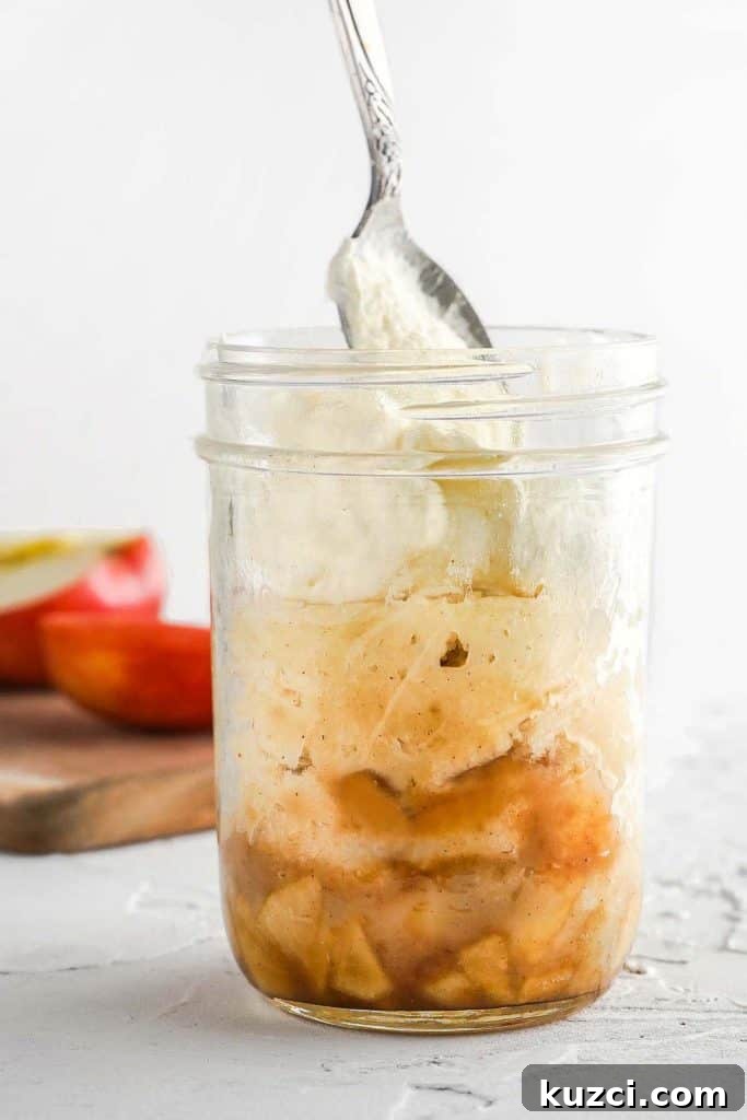 Microwave Apple Cinnamon Mug Cake Recipe 9 Side view of apples cake and whipped cream in a glass jar with spoon