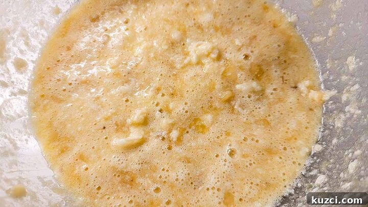 mashed banana, butter, sugar, eggs, and vanilla mixed in a bowl.