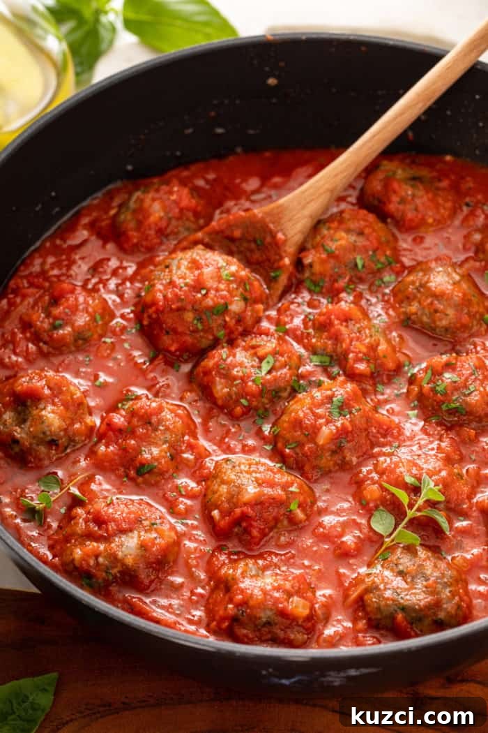 15-Minute Homemade Marinara Sauce for Pasta 8 Meatballs being stirred in a skillet of quick marinara sauce.