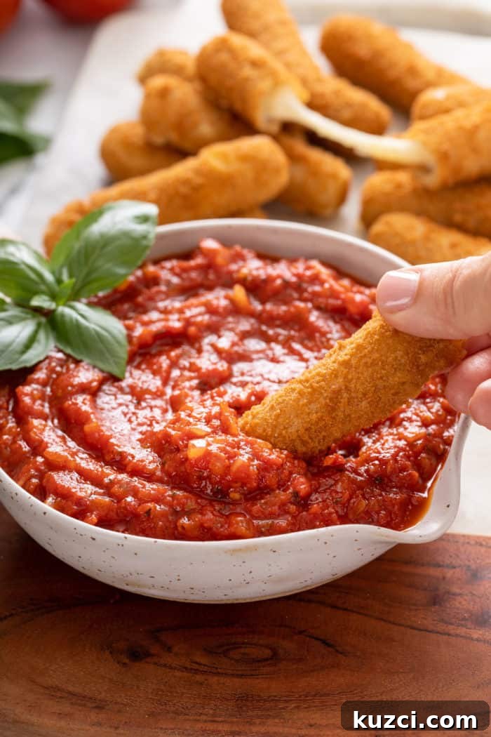 15-Minute Homemade Marinara Sauce for Pasta 10 Mozzarella stick being dipped into a bowl of quick marinara sauce.