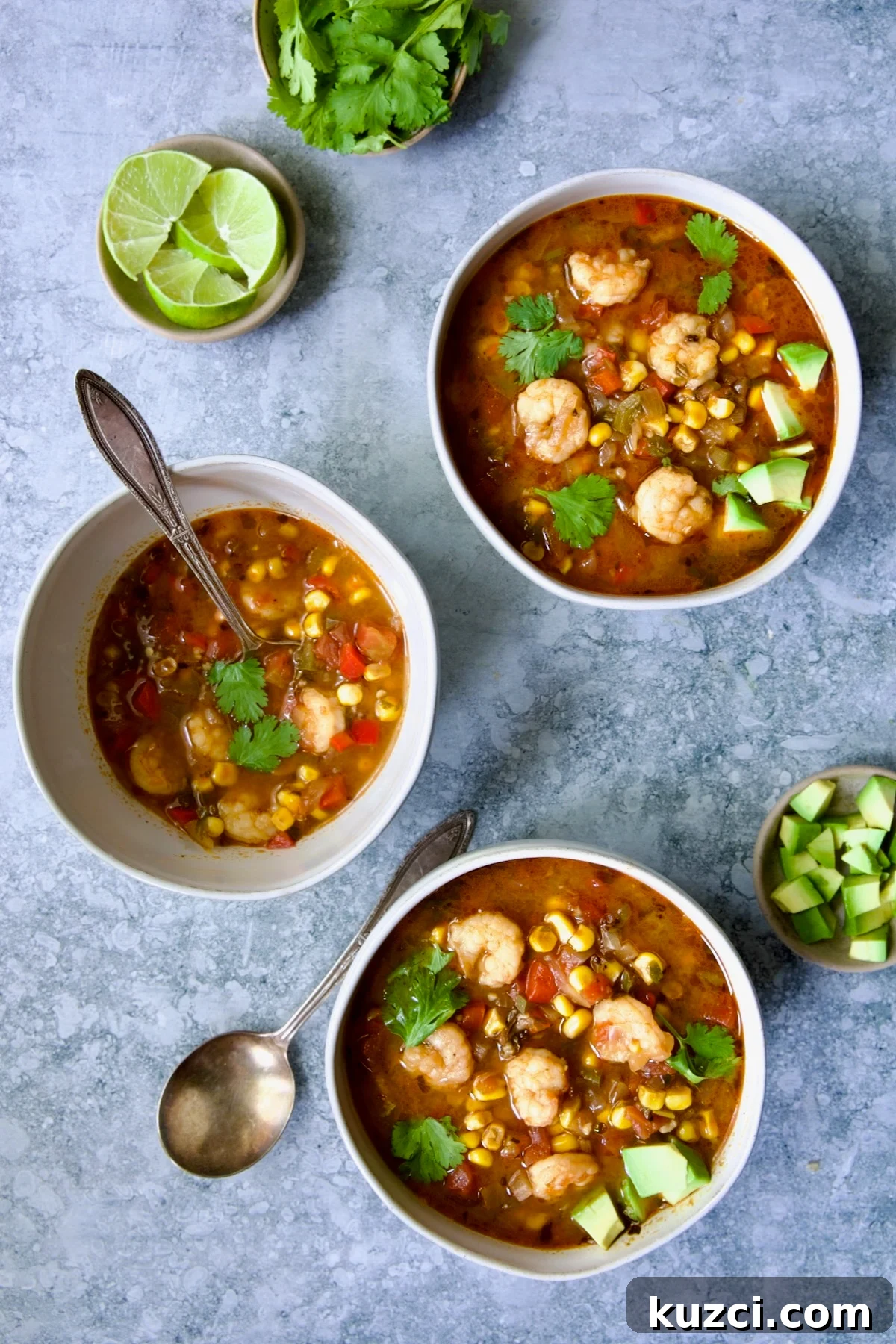 Creamy Shrimp and Corn Soup Recipe 13 Three bowls of Shrimp and Corn Soup with smaller bowls of lime wedges, cilantro and diced avocado.