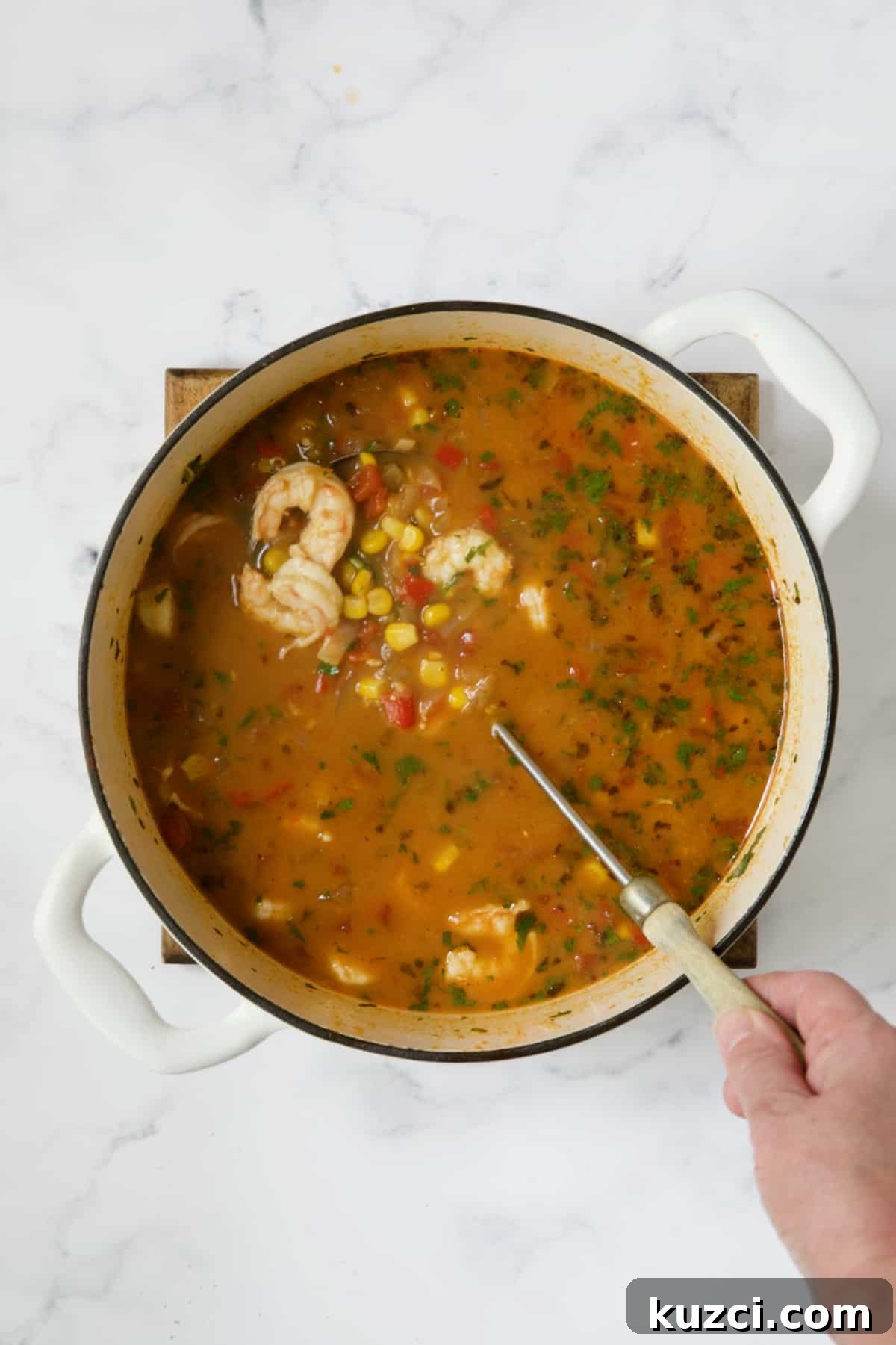 Creamy Shrimp and Corn Soup Recipe 10 Shrimp and Corn Tortilla Soup in white Dutch oven being stirred with soup ladle.