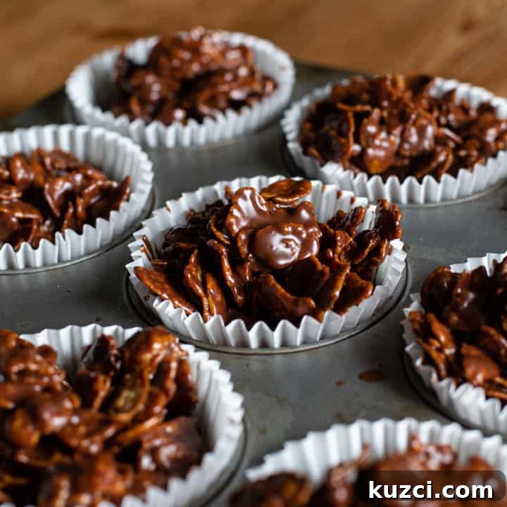 No-Bake Chocolate Cornflake Cakes Recipe 11 chocolate covered cornflake cakes in white paper cases in a metal baking tray
