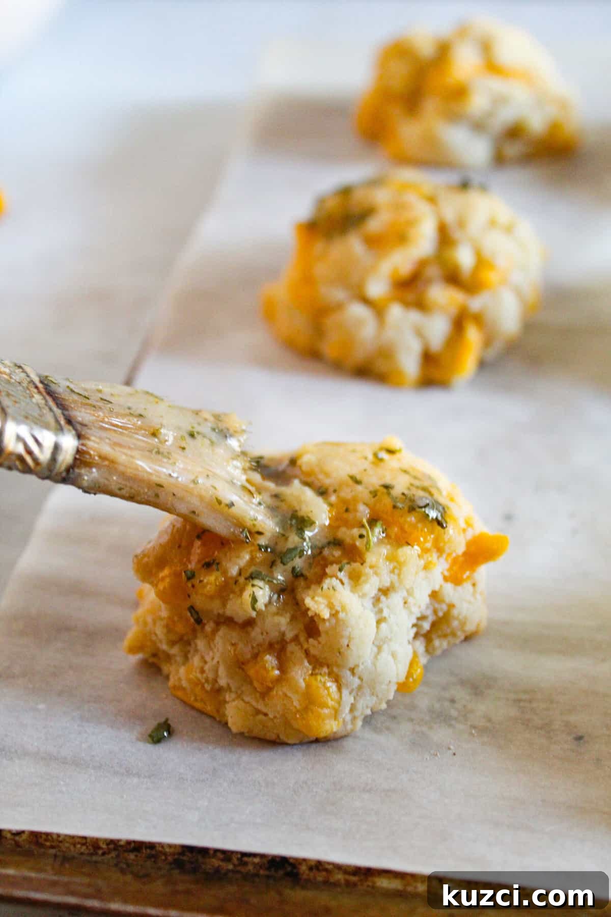 Gluten Free Dairy Free Cheddar Bay Biscuits Copycat 12 gluten free cheddar bay biscuits brushed with butter on a baking sheet.