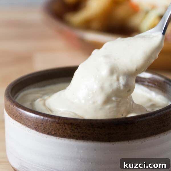 Avocado Lime Crema Recipe 11 donkey sauce in a ceramic bowl with a spoon dipping in
