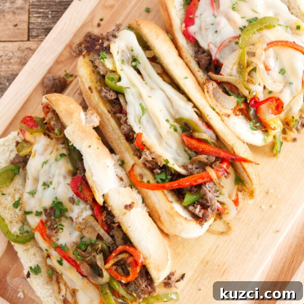 Avocado Lime Crema Recipe 9 three philly cheesesteak sandwiches laid out on cutting board, each one filled with steak, red and green peppers, melted provolone, and cheese whiz