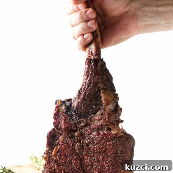 Avocado Lime Crema Recipe 10 seared tomahawk steak being held vertically from the bone, resting on cutting board