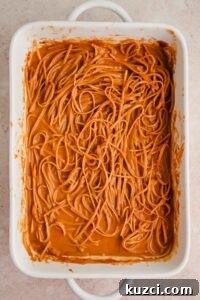 Spicy Peanut Noodles with Chili Garlic Sauce 14 noodles covered in peanut sauce in rectangular baking dish.