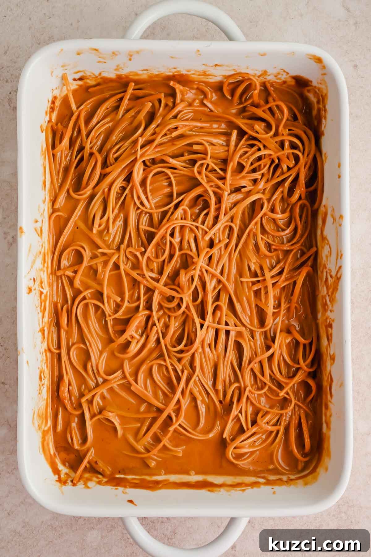 Spicy Peanut Noodles with Chili Garlic Sauce 7 noodles covered in peanut sauce in rectangular baking dish.