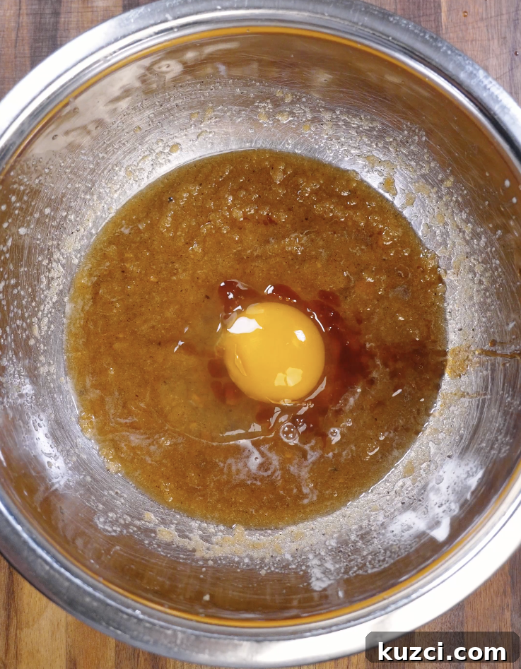 Egg and vanilla extract added to the brown butter sugar mixture, ready to be whisked into a thick and emulsified cookie dough.