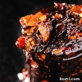 A clear glass jar overflowing with bacon jam.