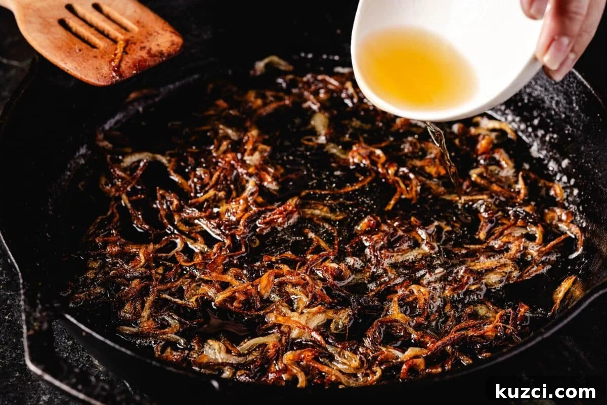 Whiskey in a bowl being poured onto pork in a cast iron skillet.