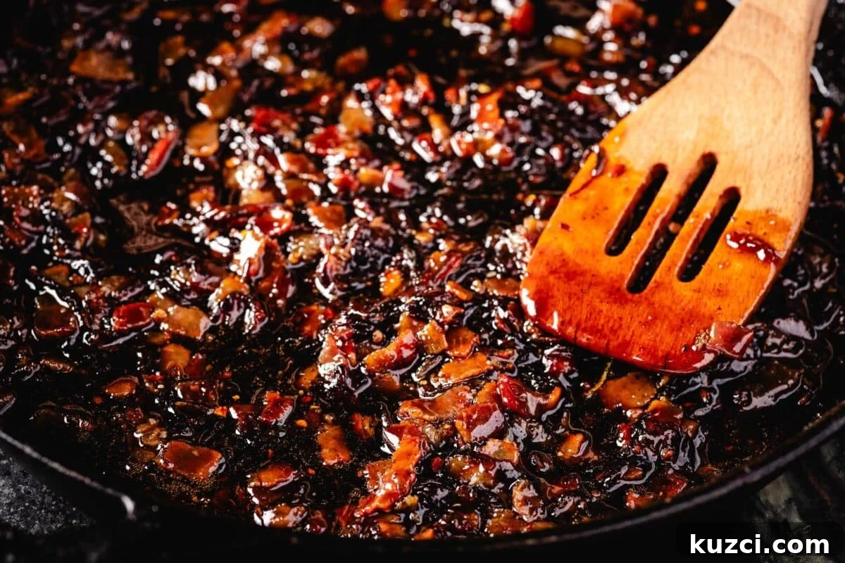 A wooden spatula stirring  pork in a skillet.