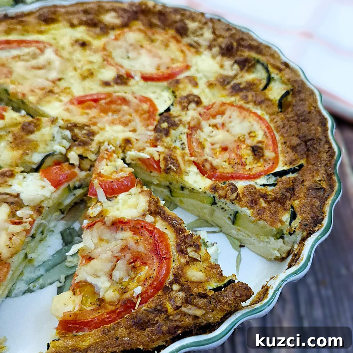 Crustless Cheesy Zucchini and Carrot Quiche 2 A cheese zucchini and carrot cake in a baking dish with a slice removed.