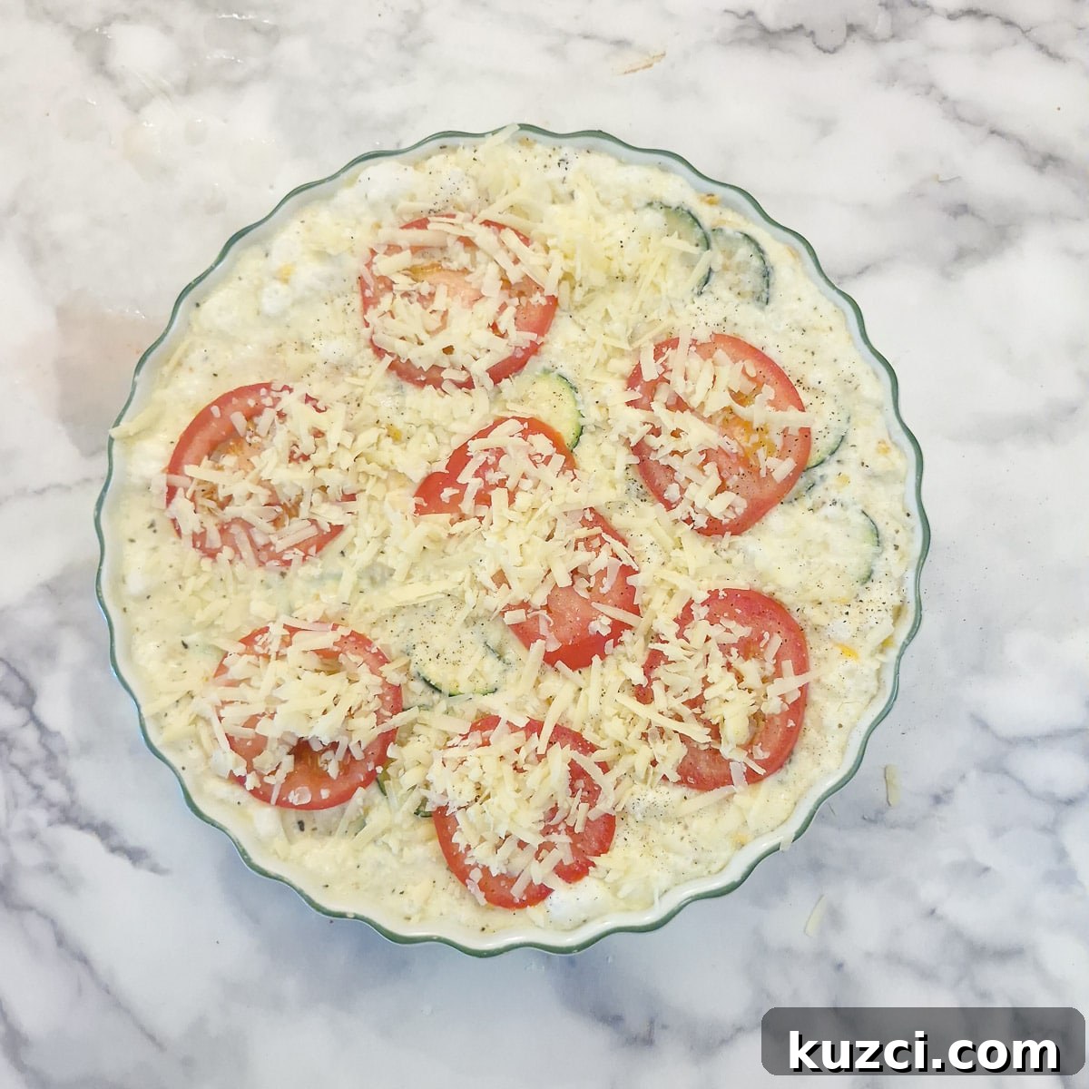 Crustless Cheesy Zucchini and Carrot Quiche 13 Slice tomatoes covered with grated cheese arranged on top of the quiche.