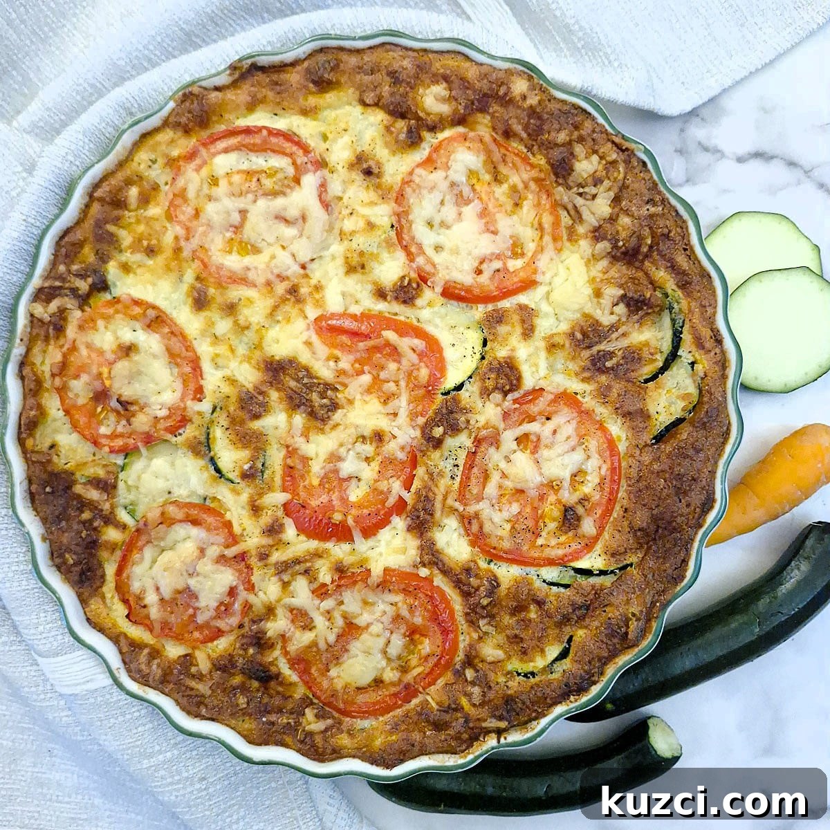 Crustless Cheesy Zucchini and Carrot Quiche 16 Overhead shot of a baked zucchini quiche with tomato and cheese topping.