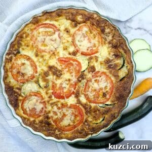 Crustless Cheesy Zucchini and Carrot Quiche 17 Overhead shot of a baked zucchini quiche with tomato and cheese topping.
