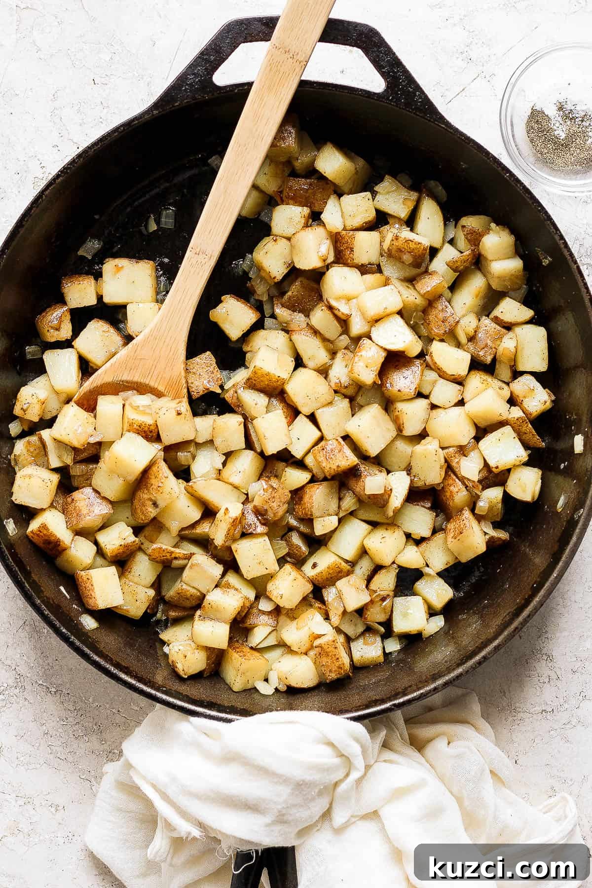 American fries in a skillet with a wooden spoon.