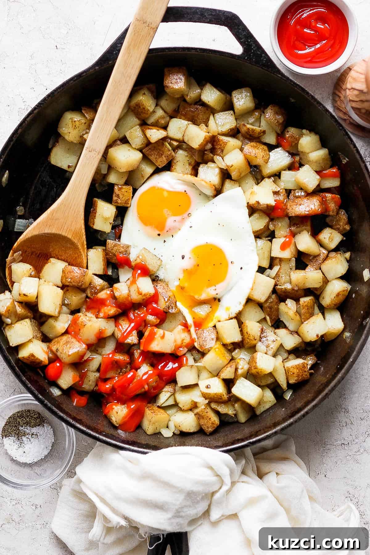 American fries in a skillet with two over easy eggs and ketchup.
