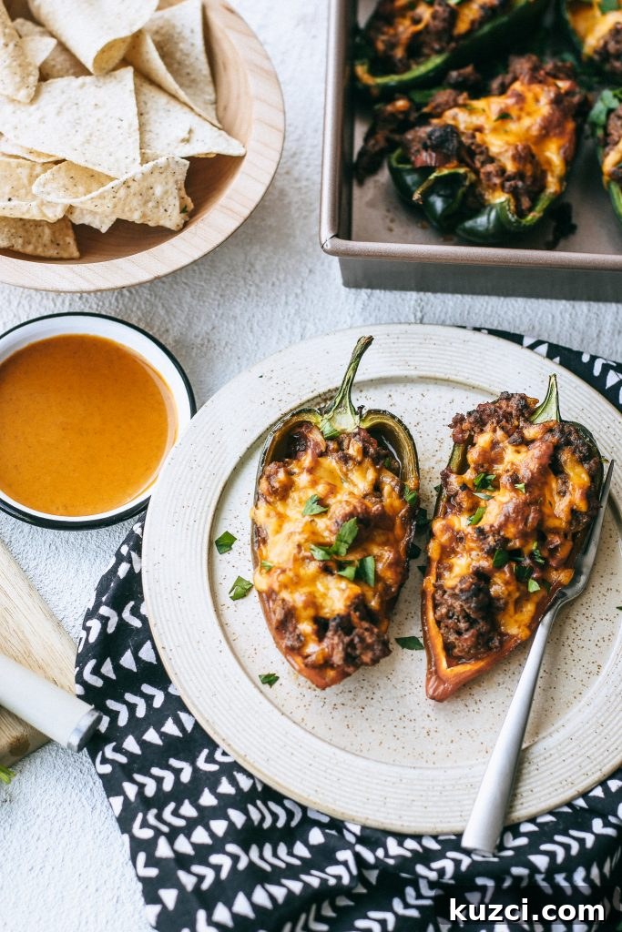Spicy Low-Carb Stuffed Poblano Peppers Recipe 5 cheesy stuffed peppers on a plate with peppers in a baking dish and a bowl of tortilla chips and a bowl of hot sauce