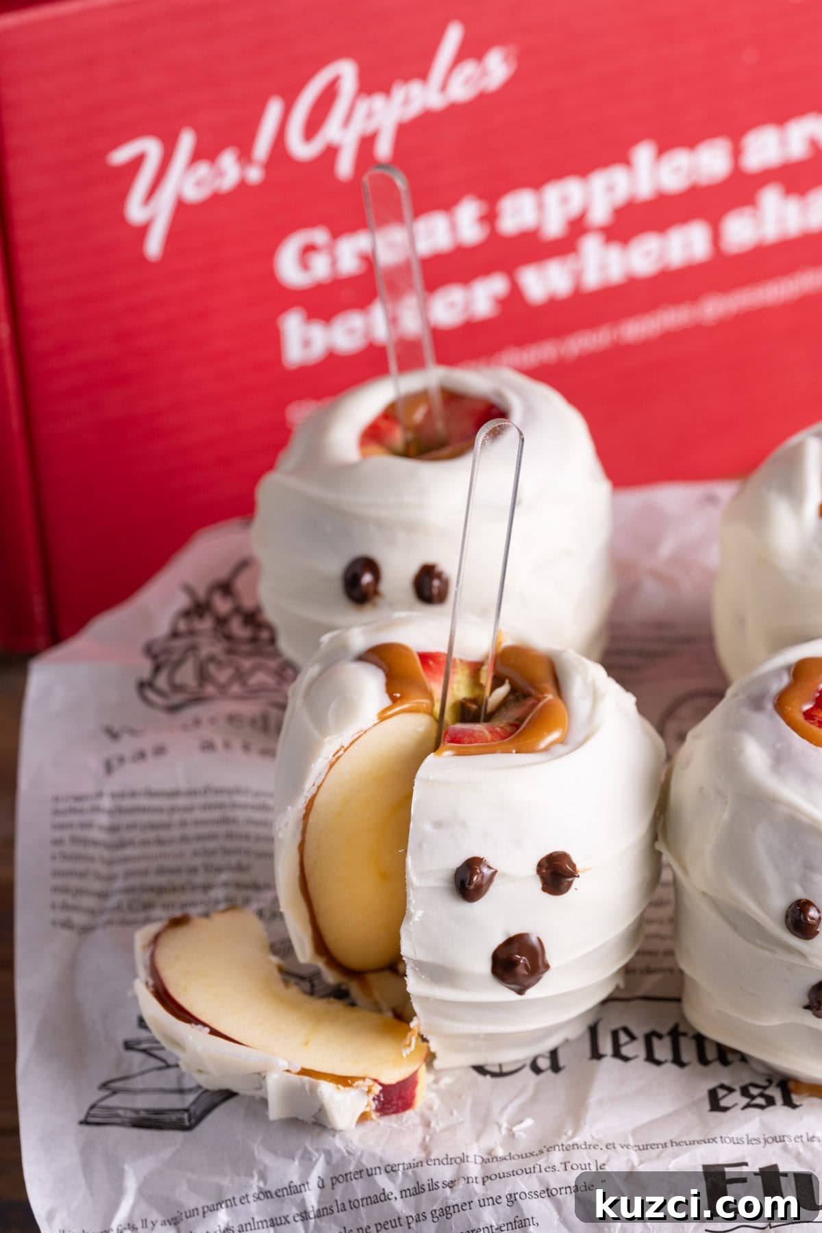 5-Ingredient Halloween Caramel Apples Recipe 2 Halloween Caramel Apples that look like ghosts with a slice cut out of the front one.