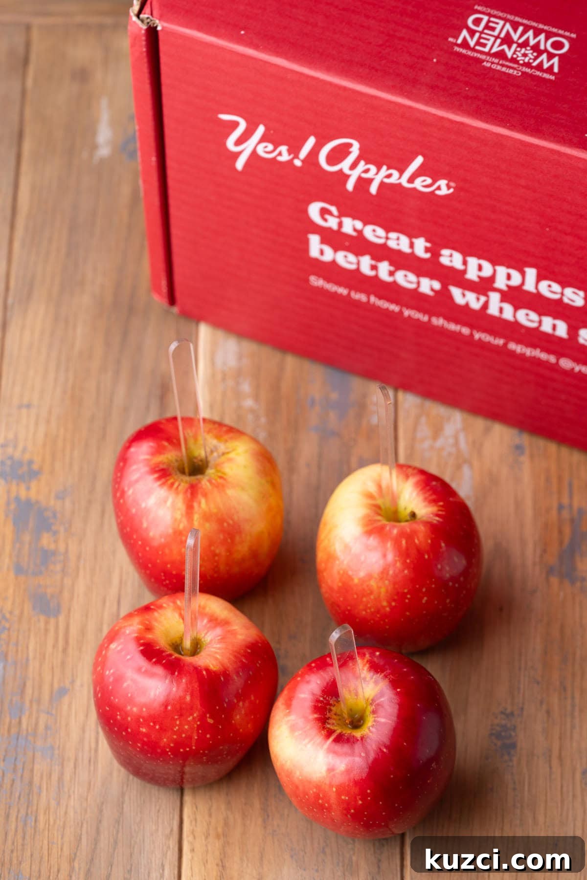 5-Ingredient Halloween Caramel Apples Recipe 6 Four apples with popsicle sticks stuck in the top next to the stem.