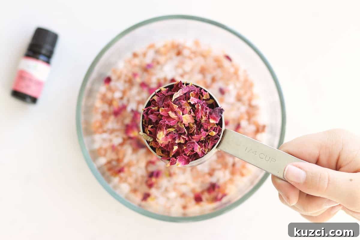 Homemade Rose Petal Bath Salts Recipe 5 rose petals being added to a bowl of sea salt, Himalayan pink salt to make bath salts.
