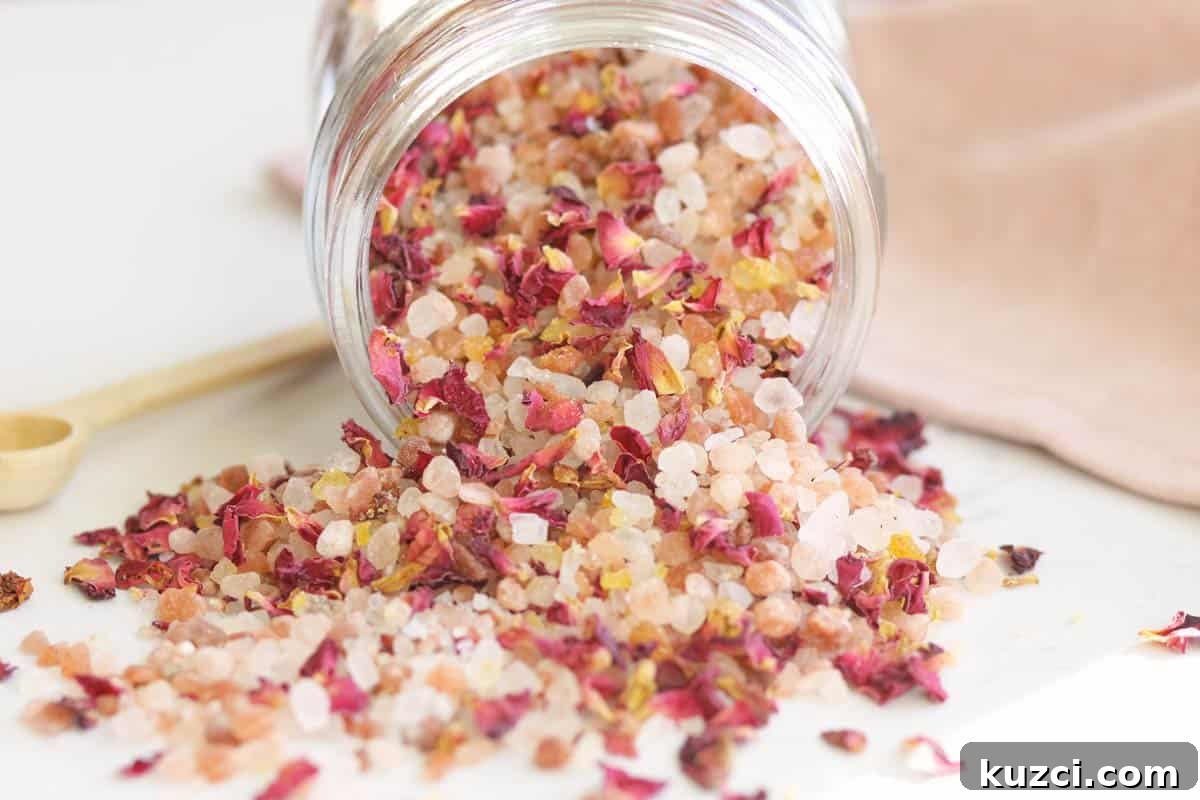 Homemade Rose Petal Bath Salts Recipe 7 a small glass jar with a wooden lid and small wooden spoon full of rose bath salts with rose petals in it.