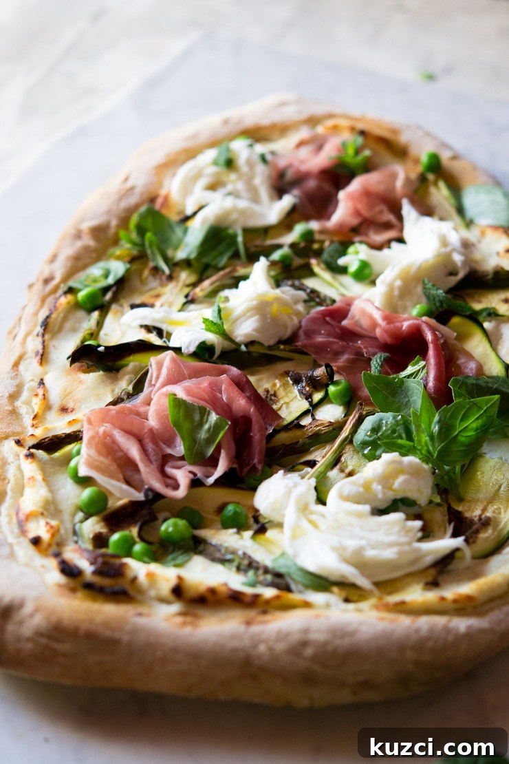 A close up of pizza with zucchini, asparagus and prosciutto