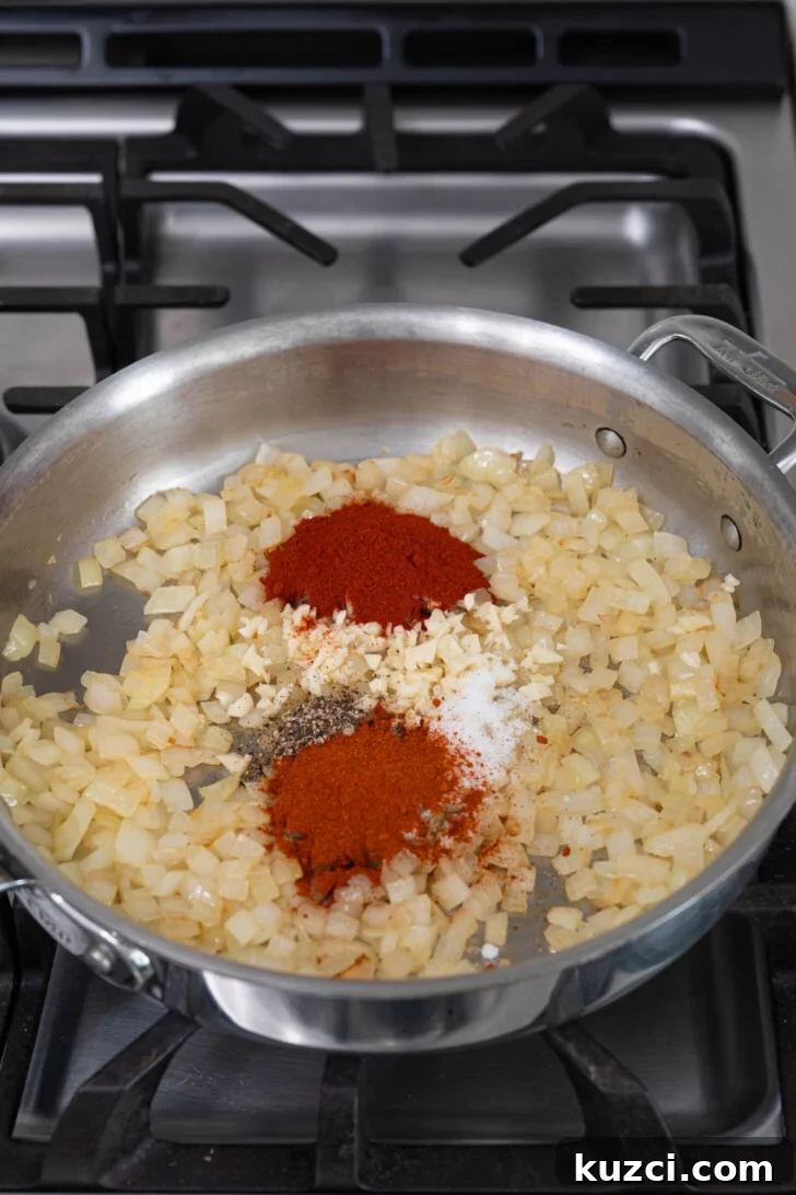 Patatas Bravas Recipe with Spicy Spanish Potatoes 5 Onions, garlic, and spices in a pan.