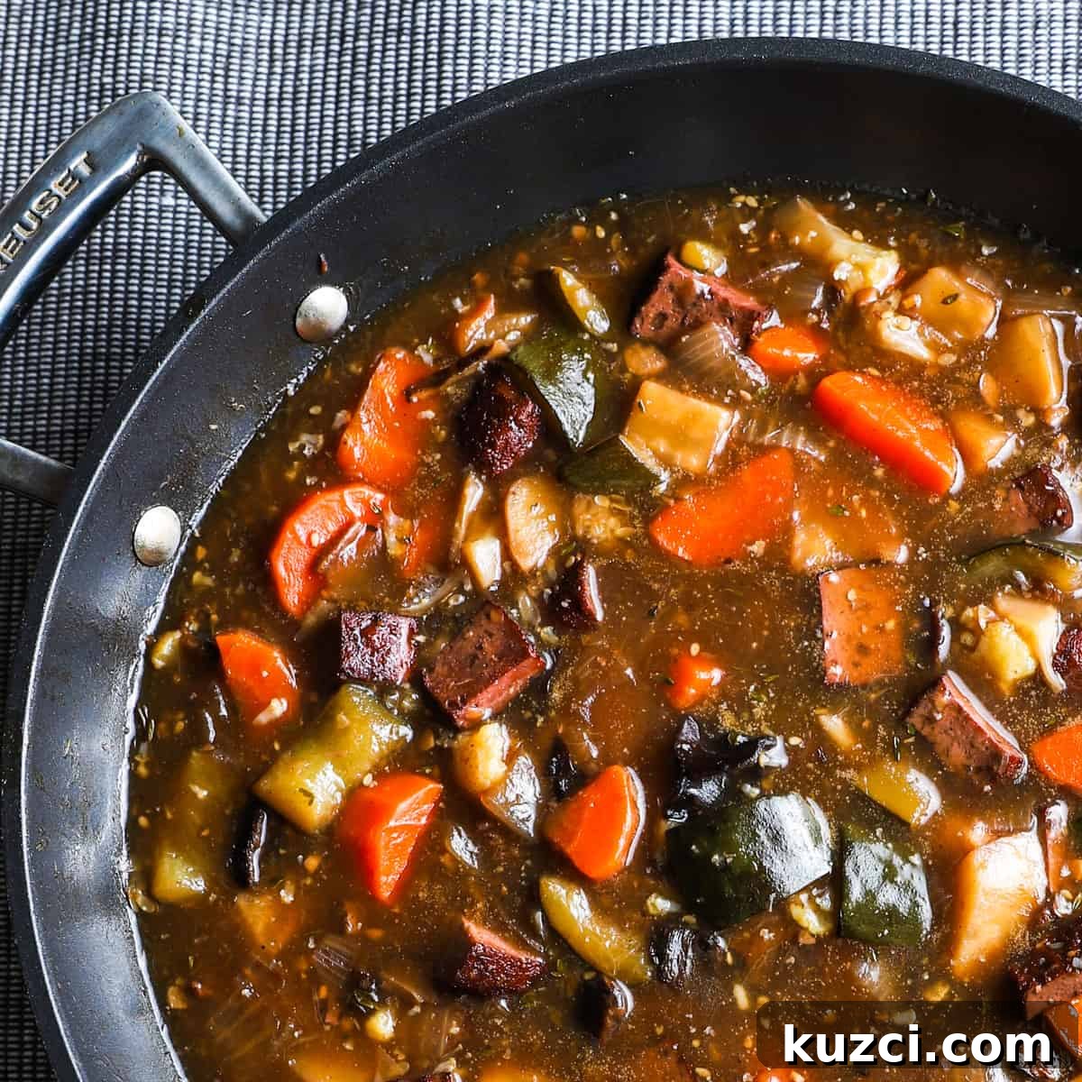 Vegan Stew with Smoked Tofu and Vegetables 2 1x1 photo of vegan stew in a black large saute pan on a grey textured table cloth.