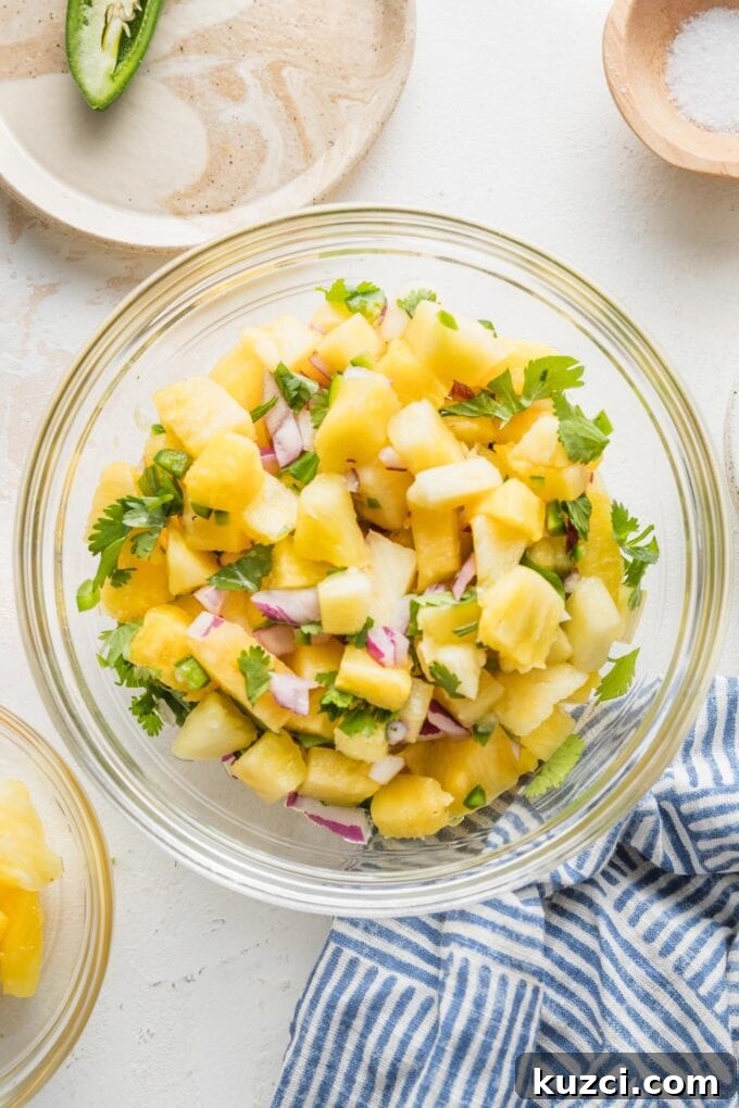 Fresh Pineapple Salsa with Jalapeño and Lime 5 Small glass mixing bowl full of pineapple salsa, with extra pineapple, salt, and jalapeno on the side.
