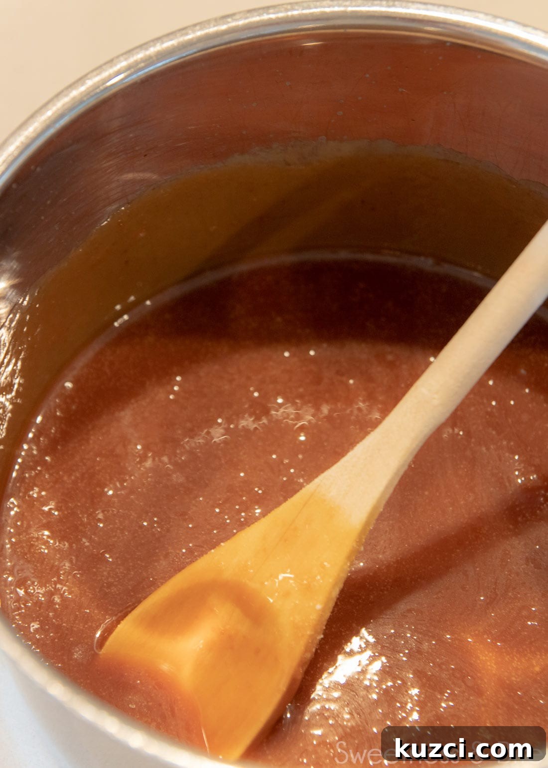 Caramel Mud Cake Recipe with Gluten Free Option 5 A saucepan with caramel sauce in it, with a wooden spoon.