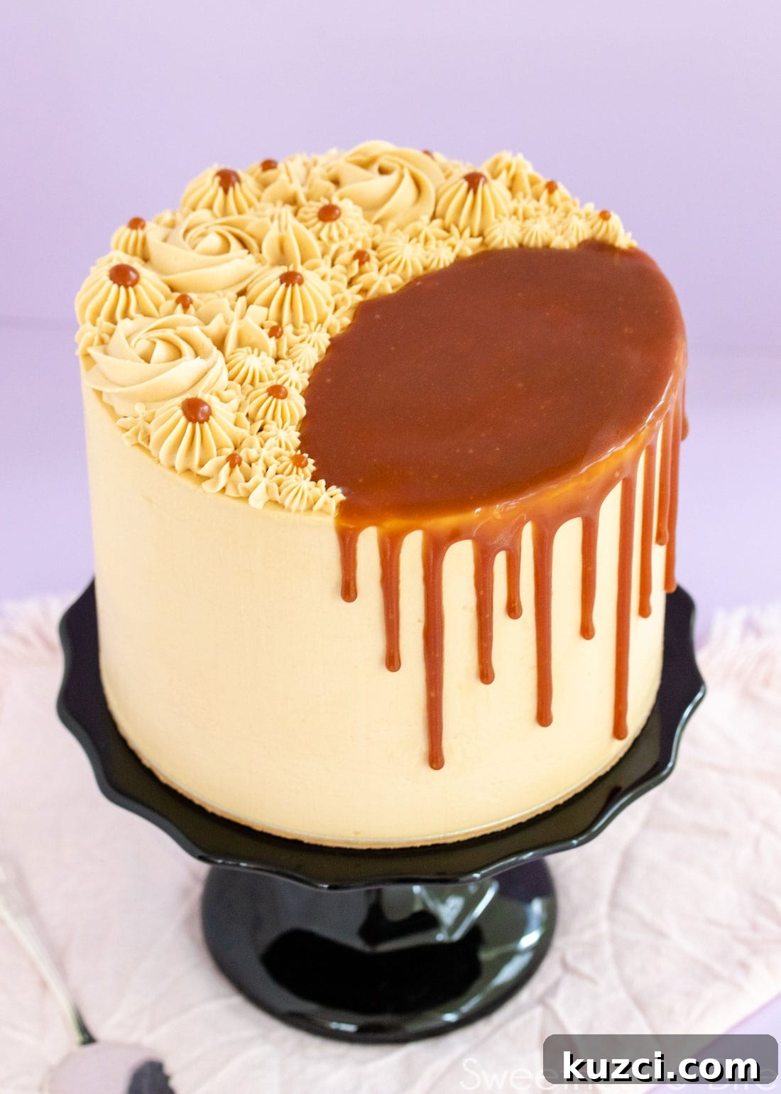 Caramel Mud Cake Recipe with Gluten Free Option 9 Caramel mud cake on a black cake stand, decorated with swirls of caramel buttercream on top, and a caramel sauce drip.