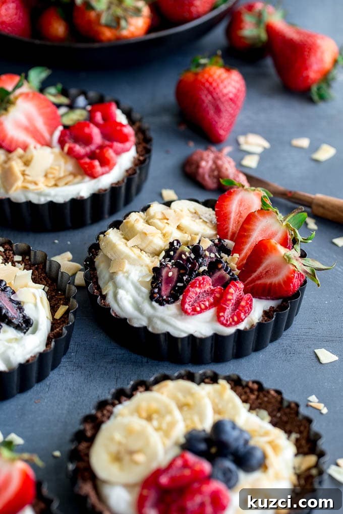 Mini fruit tarts displayed on a dark surface.