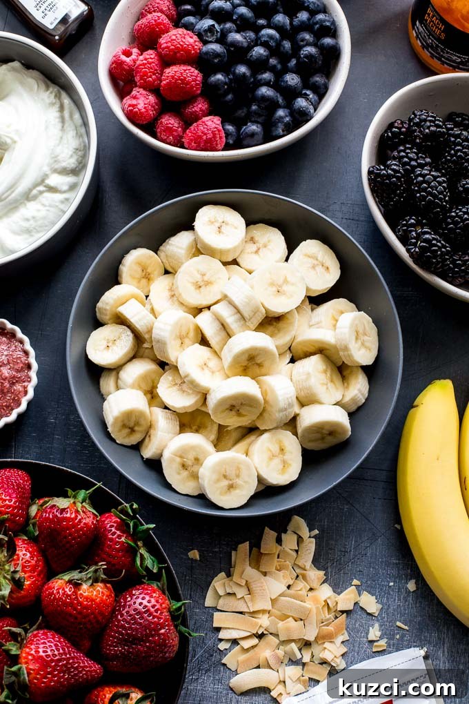 Overhead view of banana slices in a bowl, surrounded by other fruit and yogurt.