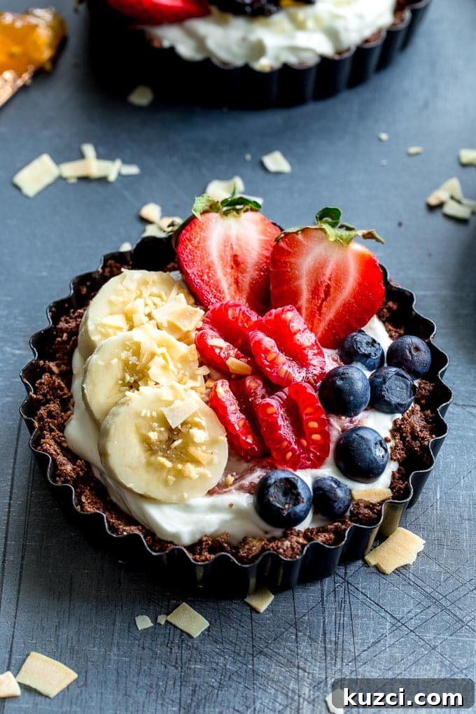 Up-close view of a mini fruit tart on a dark surface.