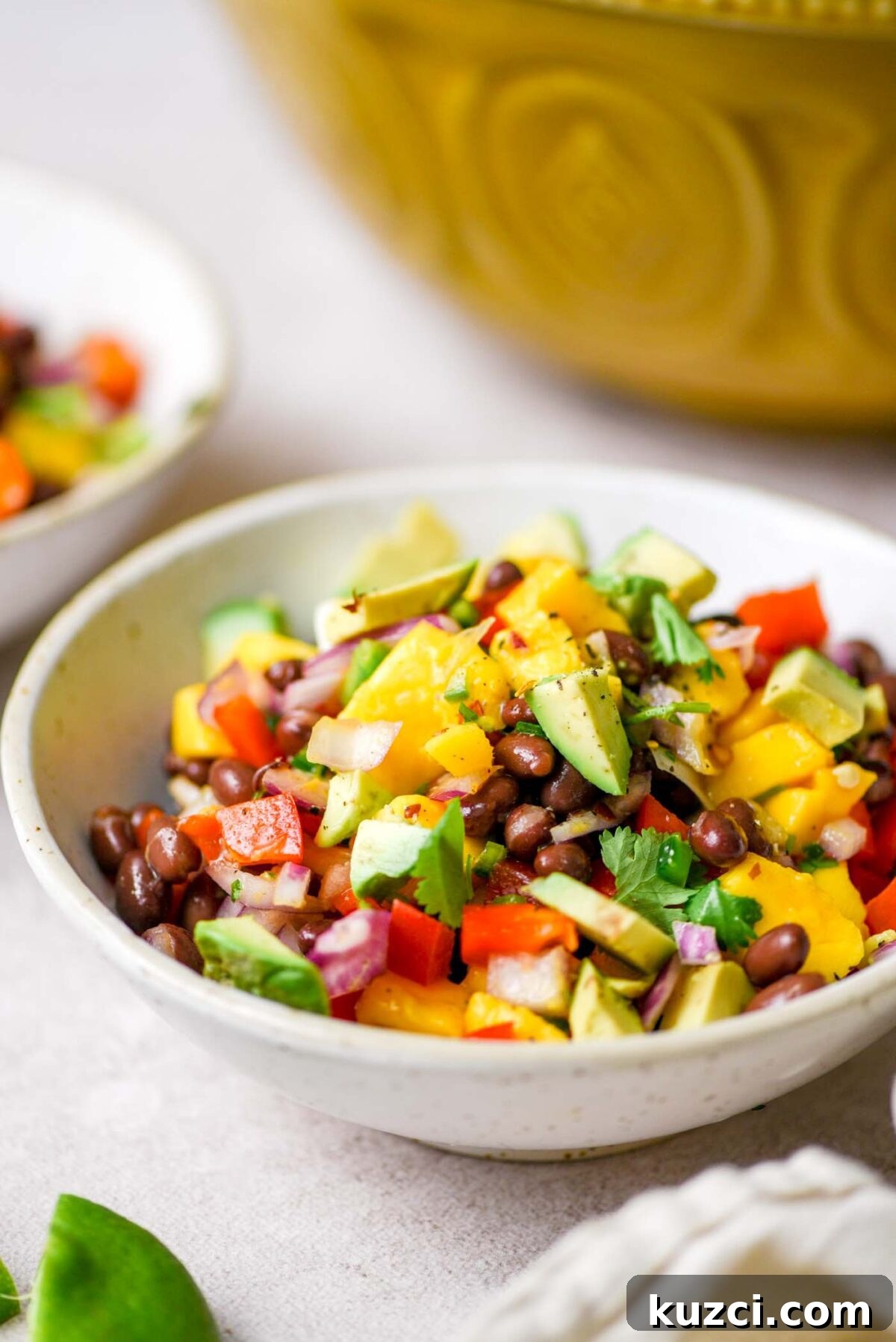 Bowl of mango black bean salad topped with avocado and cilantro.