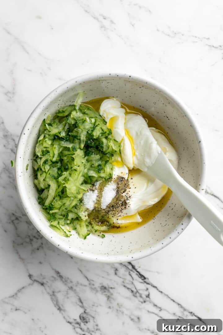 Tzatziki: Greek Yogurt and Cucumber Sauce Recipe 7 Overhead view of vegan tzatziki ingredients in bowl with spoon