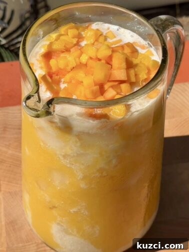 Creamy Mango Peach Agua Fresca served over ice with fresh fruit chunks