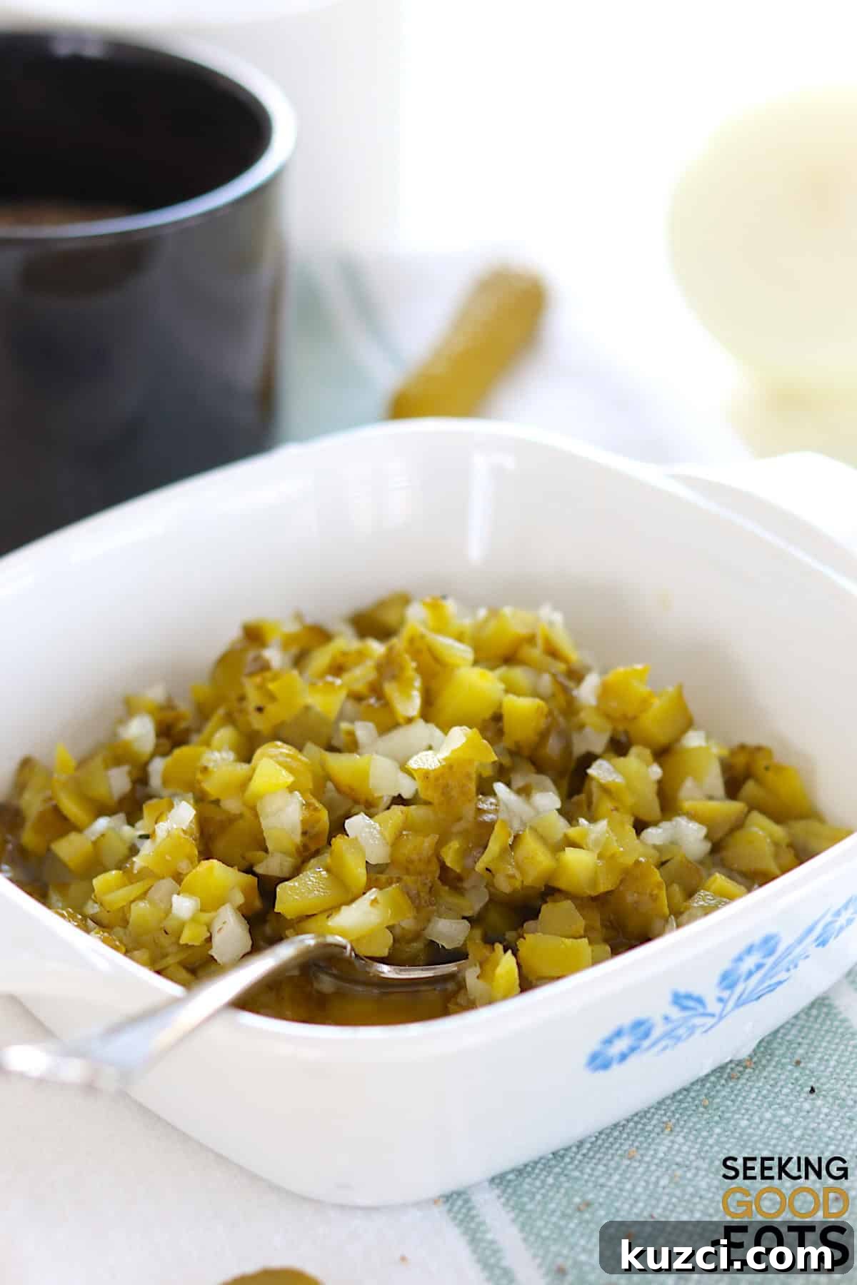 Homemade dill pickle relish served in a white square serving dish and a silver spoon.
